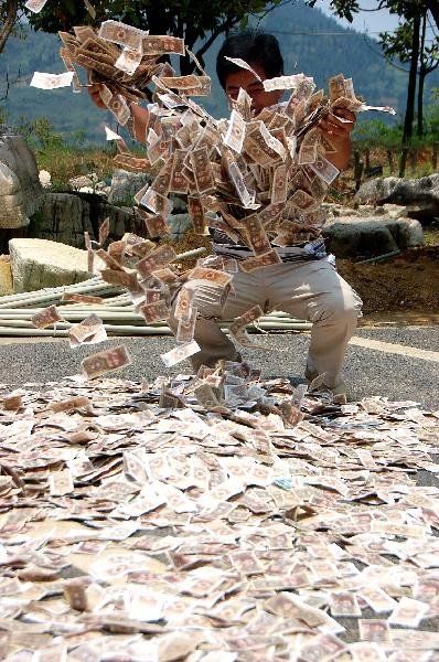 Locul unde banii "cresc" din asfalt. Un chinez a acoperit un drum cu bancnote. FOTO