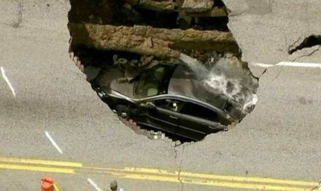 IMAGINILE ZILEI: Masina inghitita de o groapa din carosabil. Soferita a scapat cu viata. VIDEO