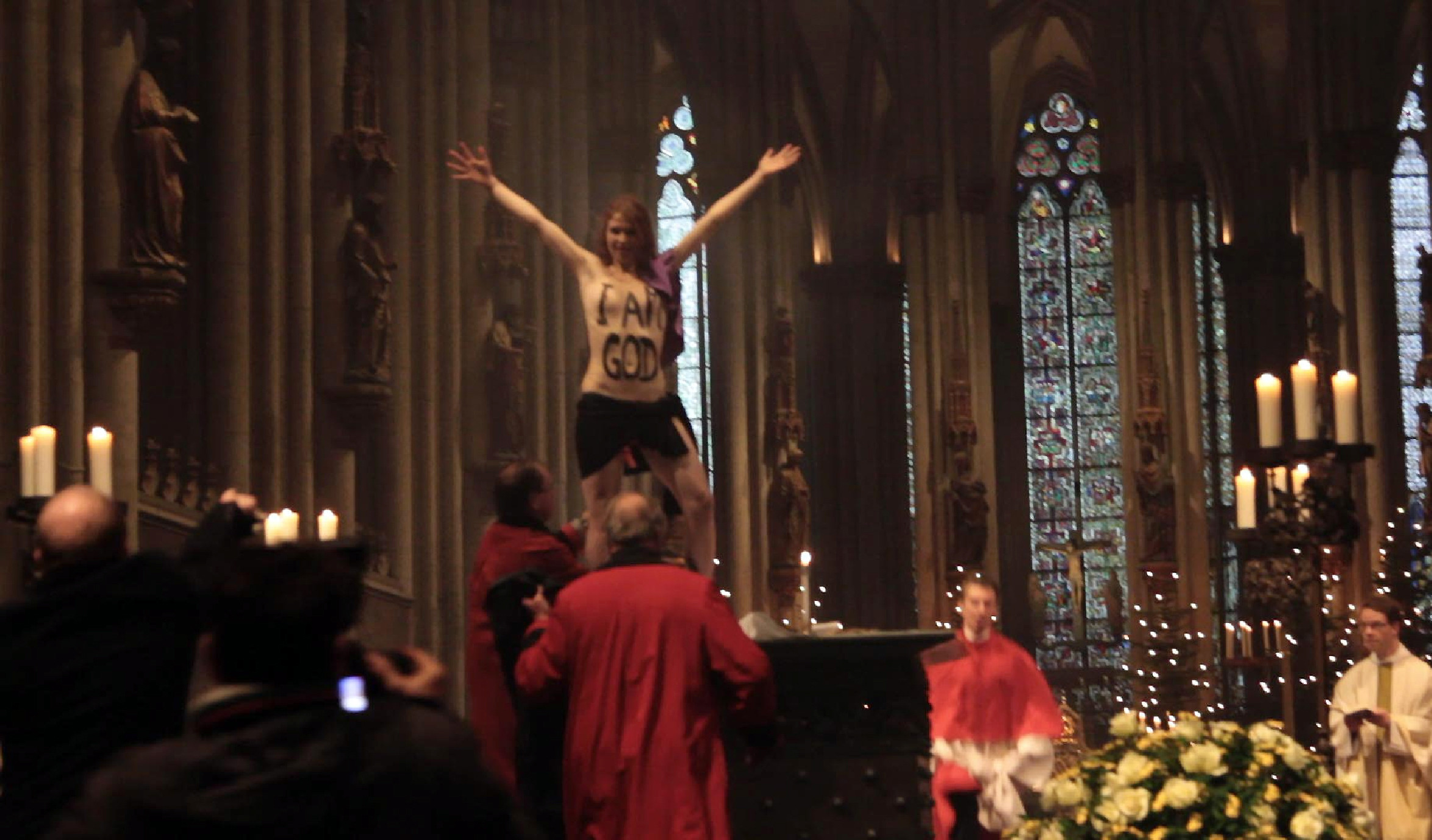 "Eu sunt Dumnezeu". Protest in sanii goi, intr-o biserica din Germania. Tanara este membra FEMEN