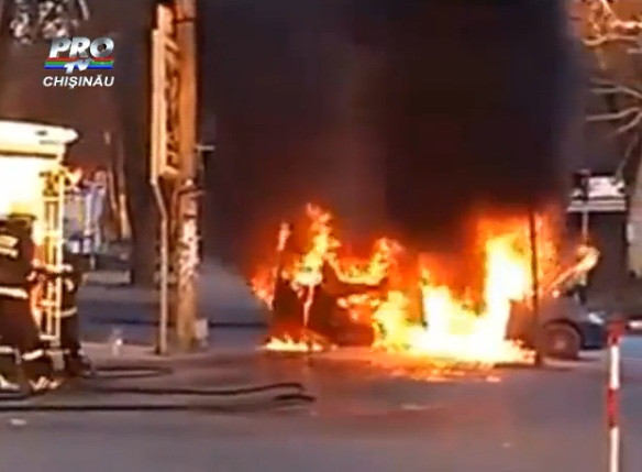 O masina in flacari traverseaza strada in Chisinau, sub privirea unei echipe intregi de pompieri