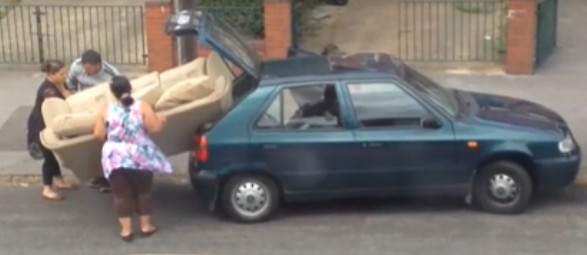 Doi oameni se lupta sa "inghesuie" o canapea in portbagajul unei masini. VIDEO viral