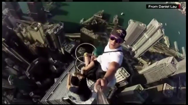 Trei tineri s-au pozat mancand banane, pe antena din varful unui zgarie-nori, in Hong Kong