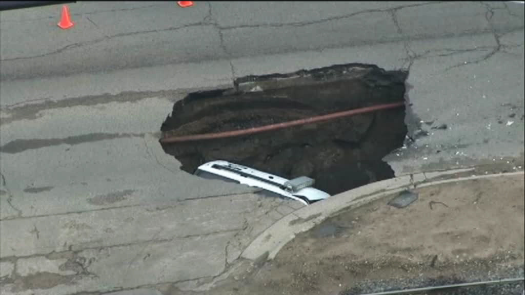 Groapa care i-ar face invidiosi si pe drumarii din Romania. O masina de politie a disparut complet in ea