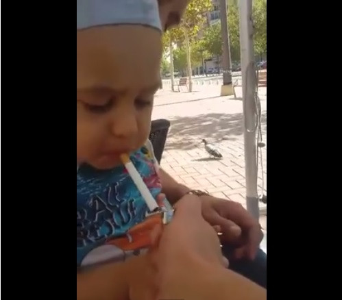 Un copil mic, filmat in timp ce este obligat sa fumeze si sa bea alcool. Reactia socanta a tatalui: "Barbat adevarat"