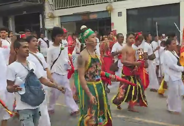Parada grotesca la un festival din Thailanda. Sute de barbati au defilat cu obrajii patrunsi de tepuse, cutite si pusti. FOTO
