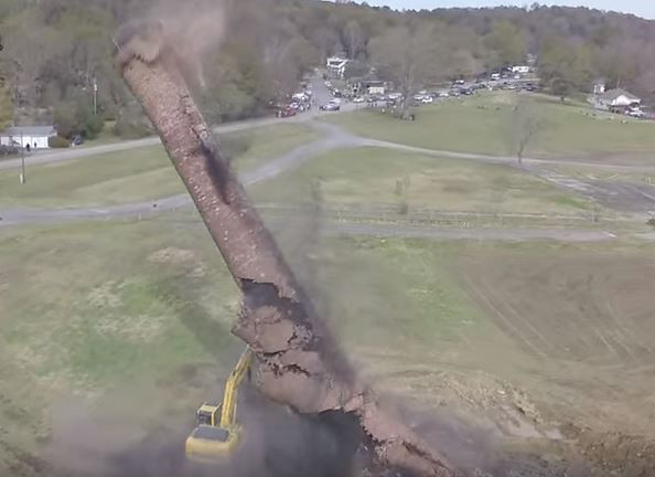 Imagini incredibile de la demolarea unui cos de fum industrial. Momentul in care se prabuseste peste barbatul din excavator