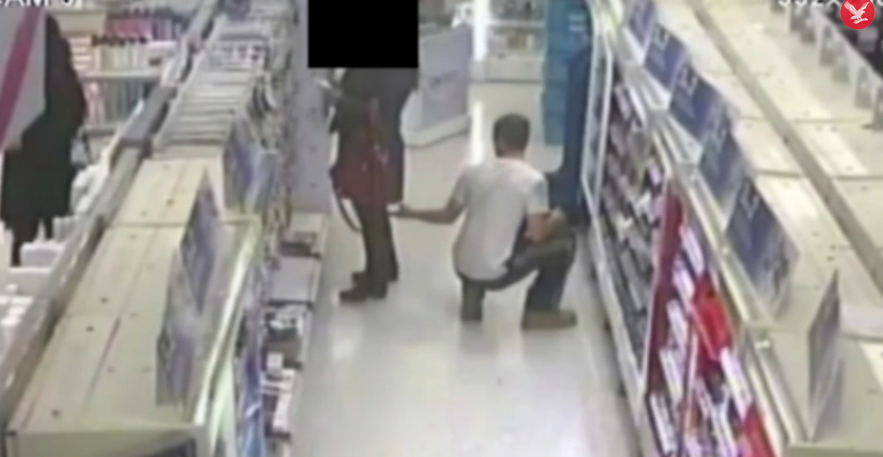 Momentul in care un barbat e surprins de camere in timp ce face poze sub fusta unei femei, intr-un magazin din Londra