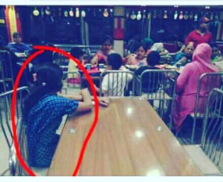 O familie bogata din Indonezia ia masa la un restaurant in timp ce servitoarea se uita la ei cum manaca de la masa alaturata