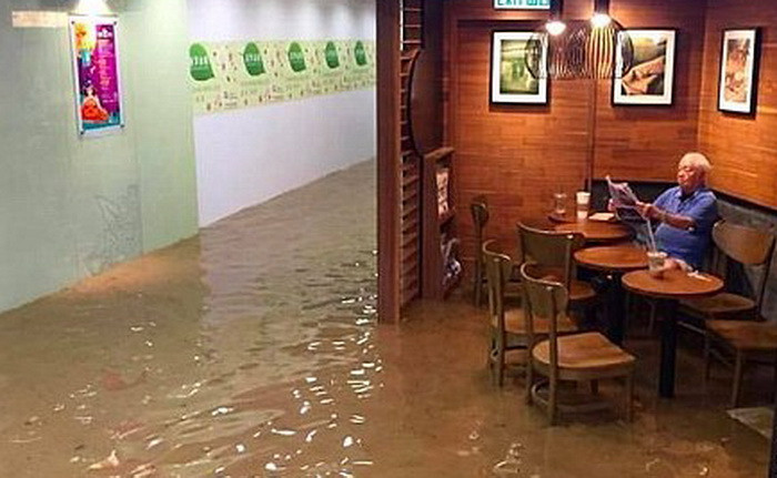 Un barbat citeste ziarul linistit intr-o cafenea inundata din Hong Kong. Povestea din spatele imaginii devenita viral