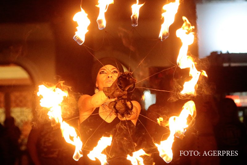 tanara jongleaza cu faclii aprinse, in cadrul festivalului Untold, desfasurat pe Cluj Arena.