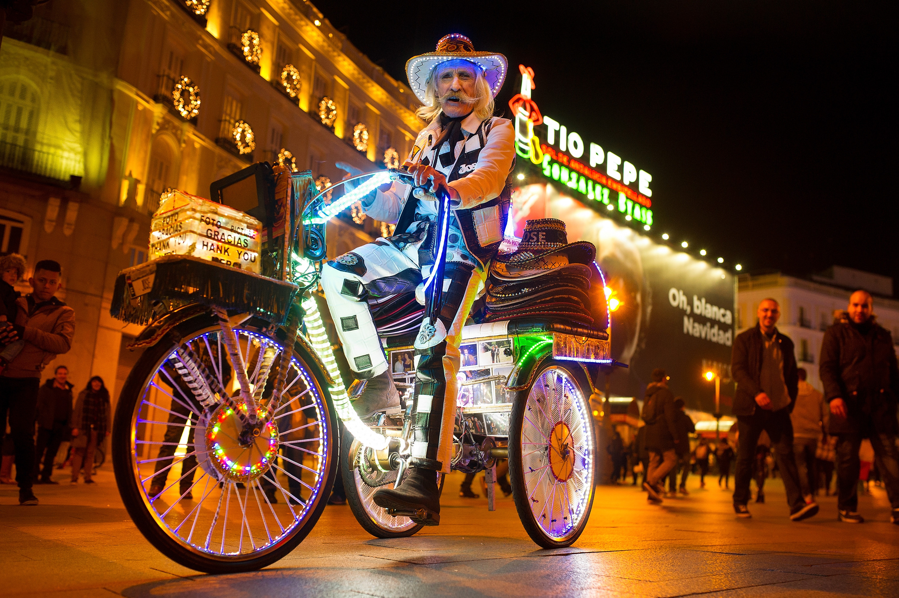 Un artist stradal merge cu bicicleta sa luminata, in Madrid, inaintea deschiderii targului de Craciun
