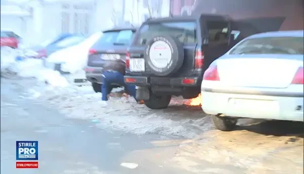 Imagini filmate in Capitala. Doi barbati incearca sa stinga cu zapada focul izbucnit sub capota unei masini