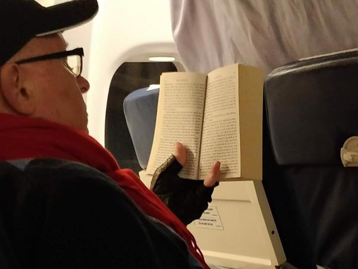 Mihai Lucan, fotografiat în avion de un pasager, în ziua de Crăciun. Cartea pe care o citea medicul