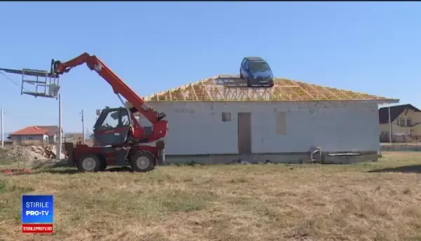 Maşină urcată pe acoperişul unei case cu motostivuitorul. Ce a vrut să facă constructorul