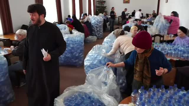 Pregătiri pentru Bobotează în parohiile din țară. Voluntarii umplu sticlele cu agheasmă