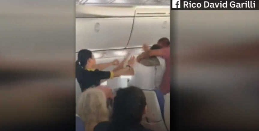 Pasager violent legat la mâini și picioare de ceilalți călători. Avionul s-a întors din drum