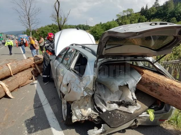 Mai mulți bușteni au căzut dintr-un camion, într-o curbă. 3 persoane, printre care și un copil, grav rănite