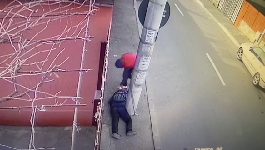 VIDEO. Momentul în care un bărbat care zace inconștient pe stradă este jefuit de un tânăr, în București