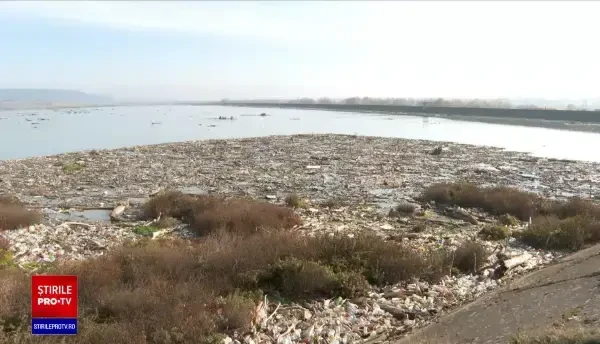 Lacul de acumulare al hidrocentralei Voila, de pe Olt, acoperit în întregime de gunoaie