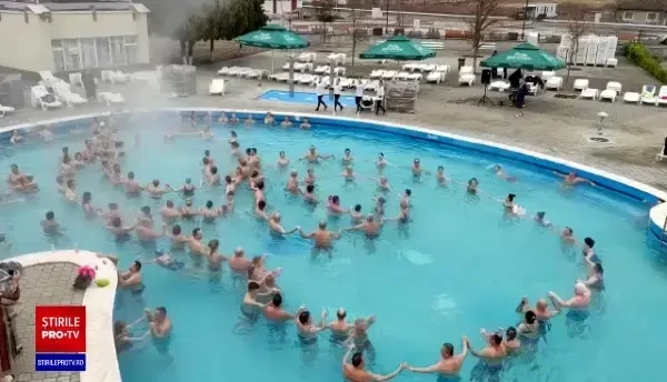 Imaginile zilei. Zeci de români în costume de baie dansează ”Hora Unirii” într-o piscină, afară. Angajații îi susțin