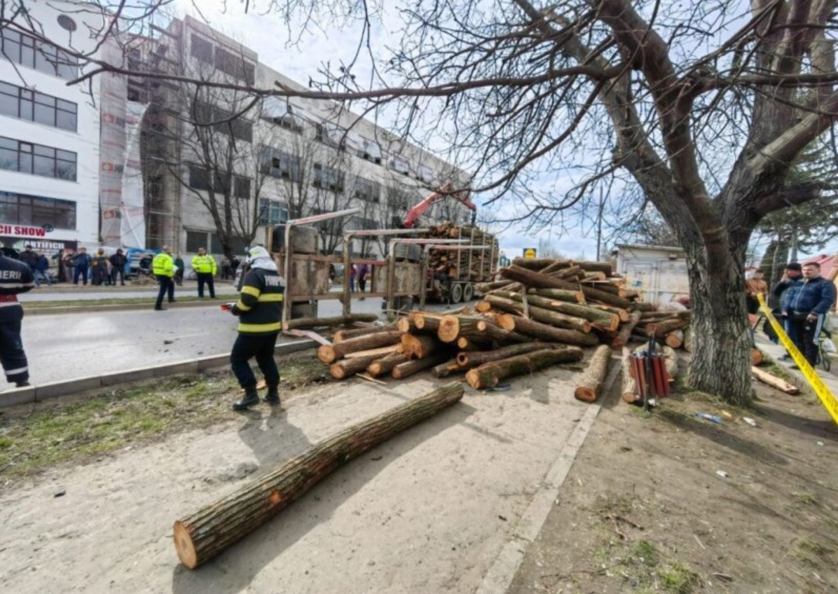 O remorcă plină cu bușteni s-a răsturnat peste doi pietoni, în Pașcani. GALERIE FOTO