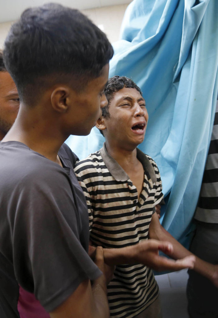 Un copil pl&acirc;nge l&acirc;ngă ruda sa ucisă &icirc;n timpul atacurilor, la Spitalul Martirilor Al-Aqsa / foto: Ashraf Amra/Anadolu via Getty Images Translated with DeepL