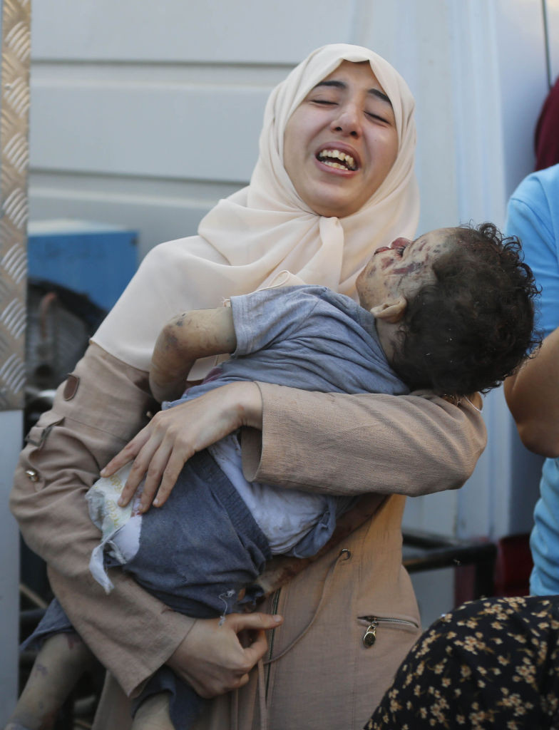 O femeie pl&acirc;nge &icirc;n timp ține &icirc;n brațe trupul copilului ei care și-a pierdut viața &icirc;n urma atacurilor israeliene la Spitalul Martirilor Al Aqsa / foto: Ashraf Amra/Anadolu via Getty Images