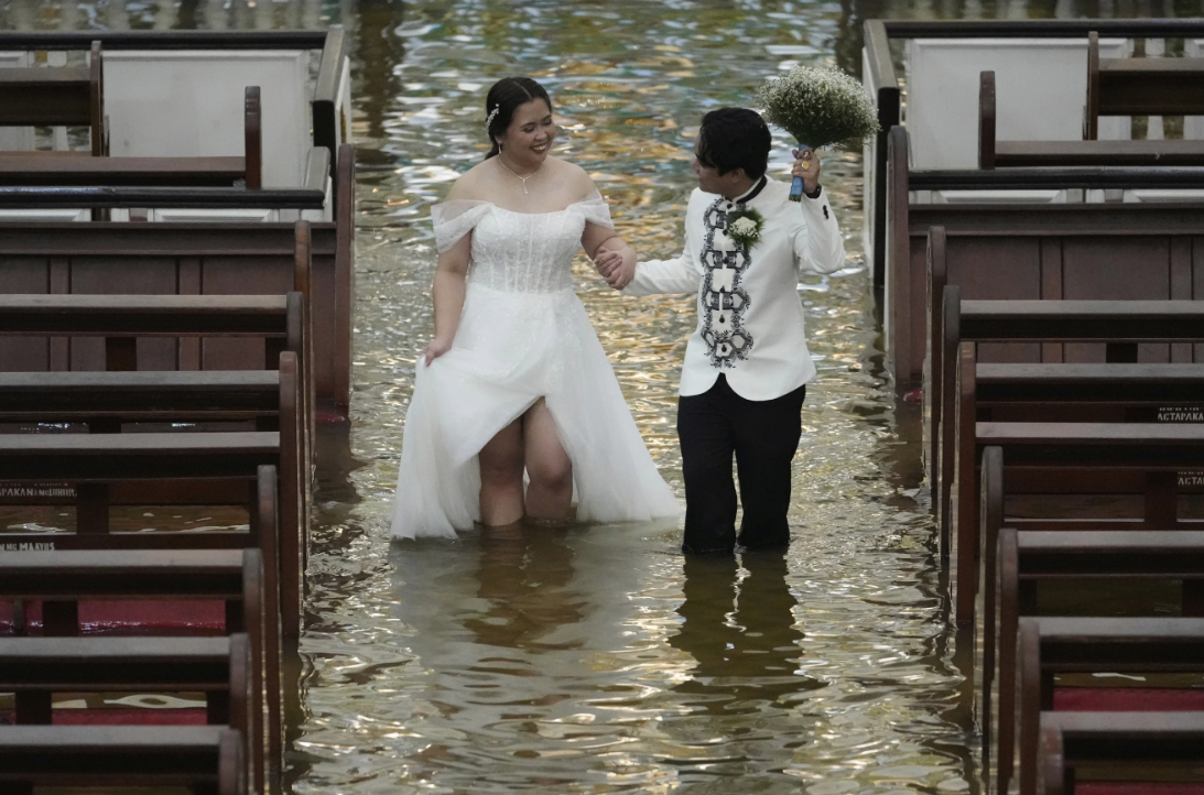 „Este doar un test”. Un cuplu, surprins de fotografi mergând pe culoarul unei biserici inundate, în ziua nunții