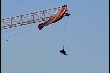 Un parapantist a rămas suspendat la 60 de metri după ce parașuta sa s-a încurcat într-o macara, în China. VIDEO